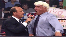 a man in a suit and tie is talking into a microphone while another man shouts