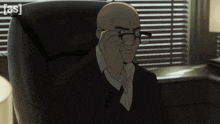 a bald man wearing glasses sits in a chair with the letters a and s on the back