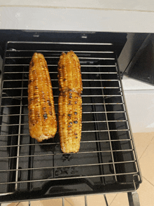 two corn on the cob are being cooked on a grill with a sauce on them
