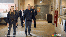a group of firefighters standing in a hallway with nbc written on the bottom right