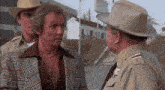a man in a plaid jacket and cowboy hat talks to a sheriff