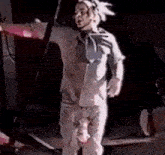 a man in a white shirt and pants is standing on a stage with his pants down .