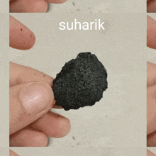 a person is holding a piece of charcoal and the word suharik is above it