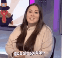 a woman with long hair is sitting in front of a turkey and says gobble gobble .