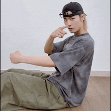 a man wearing a tie dye t-shirt and a black hat is sitting on the floor