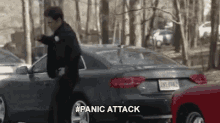 a police officer is standing next to a car in a parking lot and says panic attack .