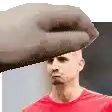 a man in a red shirt is being slapped in the face by a hand .