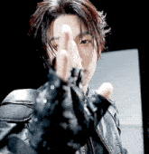 a man wearing a black leather jacket and black gloves is making a middle finger gesture