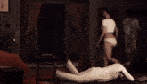 a woman in white underwear is standing next to a mannequin in a room