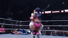 two women are wrestling in a wrestling ring and one of them is hugging the other .