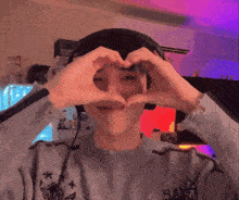 a person wearing headphones making a heart with their hands
