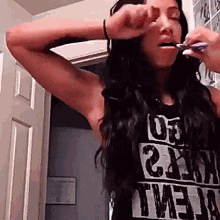 a woman brushing her teeth wearing a shirt that says ' twenty ' on it