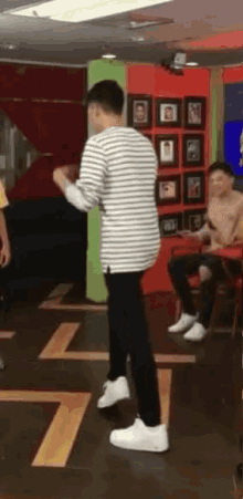 a man in a striped shirt and white shoes is dancing