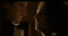 a man and a woman are looking at each other in a dark room on a television screen .