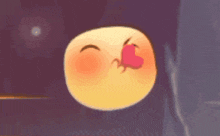 a cartoon smiley face is blowing a kiss and has a red heart on its nose .