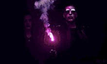 a man in sunglasses is holding a purple firework display