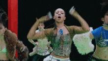 a group of women are dancing and one of them is wearing a blue shirt with the letter t on it