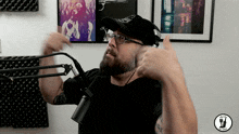 a man wearing glasses and a hat is giving a thumbs up in front of a mic