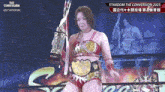 a woman in a wrestling ring is holding a trophy and a belt .