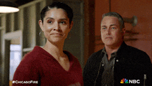 a man and a woman are standing next to each other with a chicago fire advertisement in the background