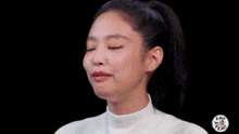 a woman with her eyes closed and her mouth open is wearing a white turtleneck .