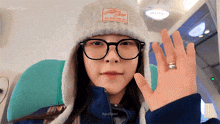 a woman wearing glasses and a hat with a label that says ' sunny king ' on it