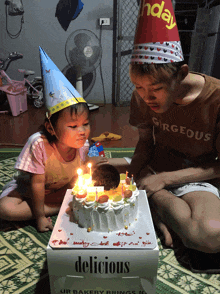 a boy and a little girl blow out candles on a birthday cake