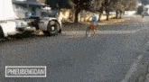 a man is riding a bicycle on a street next to a truck .