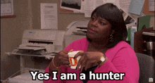 a woman in a pink shirt holds a cup of coffee and says " yes i am a hunter "