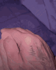 a close up of a person 's hand with a tattoo of a cross on it .