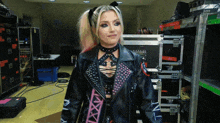 a woman wearing a black leather jacket with a pink strap that says nxt