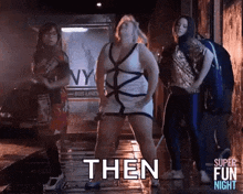 a group of women are dancing in a dark alleyway and one of them is holding a microphone .