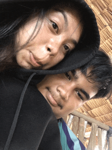 a man and a woman are posing for a picture and the man is wearing a black hoodie