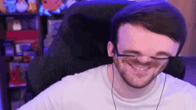 a man wearing glasses is smiling while sitting in a chair in front of a computer .