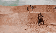 a man and woman are hugging in the desert with a horse in the background .