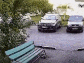 two cars are parked in a parking lot next to a green bench