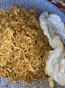 a plate of noodles and eggs on a blue and white plate