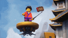 a lego figure is flying in the air holding a selfie stick