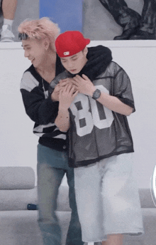 a man wearing a jersey with the number 80 on it is hugging another man