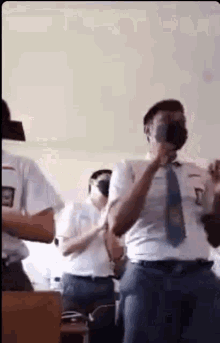a group of students are standing in a classroom wearing face masks .