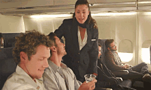 a stewardess serves a drink to a man on a plane