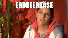 a woman is sitting in front of a plant with the word erdbeerkase written on the bottom .
