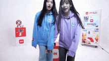 two girls standing next to each other wearing hoodies that say idn