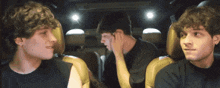 three young men are sitting in the back seat of a car talking