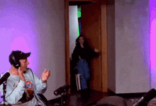 a man wearing headphones is talking into a microphone while a woman is standing in the doorway .