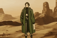 a man in a green coat stands in the desert holding a piece of paper that says ' a ' on it