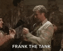 a man is dancing in front of a group of people with the words `` frank the tank '' written on the screen .