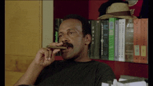 a man is smoking a cigar in front of a bookshelf with a book titled encyclopedia