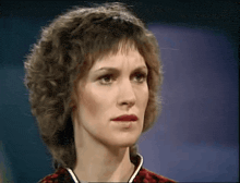 a woman with curly hair looks at the camera