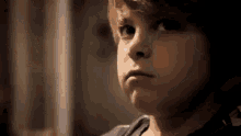 a young boy is making a funny face while looking at something .
